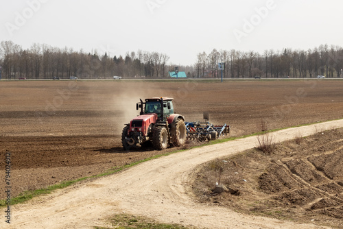 Red tractor is plowing a field closeup