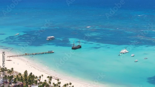 Aerial view of beautiful tropical white sand Los Corales beach in Punta Cana. Moored pirate ship in turquoise Caribbean sea water. Best attractions and excursions in Dominican Republic photo