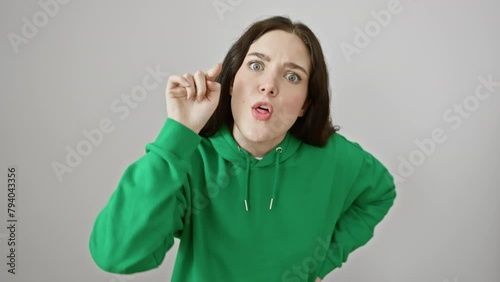 Furious young woman in sweatshirt angrily pointing at you, displeased expression dominates her face as she stands isolated on white background. photo
