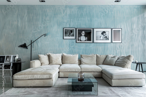 A contemporary living room with a sky-blue brushed wall texture. The room features a modular sectional sofa in beige, a glass top side table, and a minimalistic black floor lamp. 