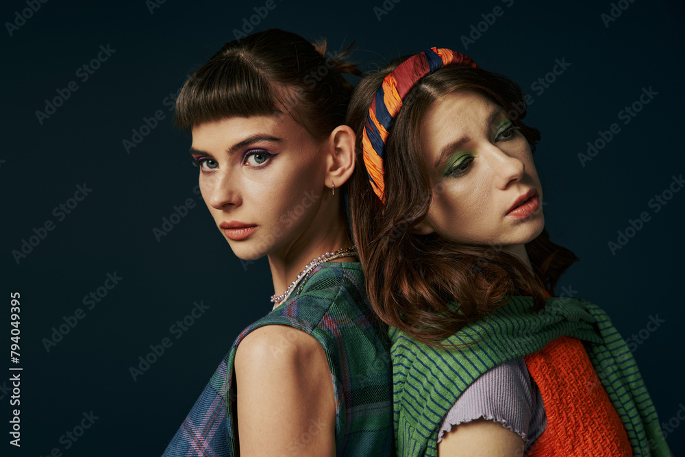 A beautiful lesbian couple with colorful makeup standing together.