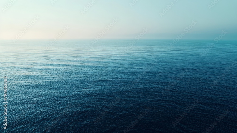 Obraz premium An aerial view of a calm sea at dawn, the subtle gradient of blues creating a tranquil, minimalist landscape that invites contemplation.