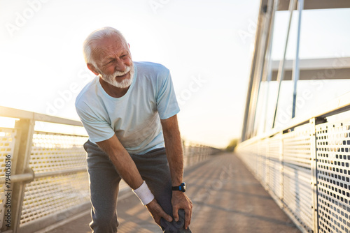 Shot of a mature man experiencing knee pain. mature man experiencing knee pain while exercising outdoors.