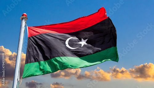 Die Fahne von Libyen, flattert im Wind, isoliert, gegen den blauen Himmel photo