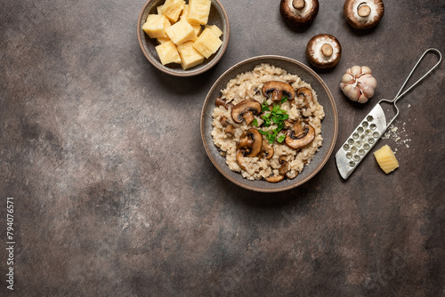 Risotto with mushrooms in a bowl on a dark grunge background. Top view, flat lay, banner.