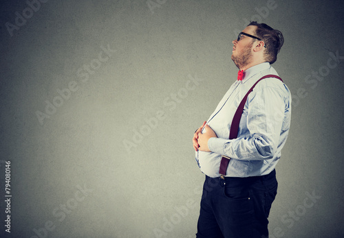 Young man feeling bloated with arms on belly 