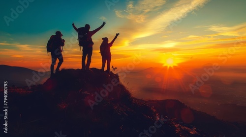 silhouette of happy hikers on mountaintop enjoying breathtaking sunset view © Bijac