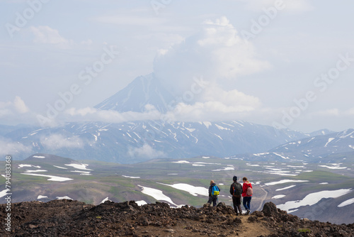 Hikers on a mountain path. View from Gorely volcano to Vilyuchinsky volcano, Kamchatka Krai, Russia. Travel, tourism and hiking on the Kamchatka Peninsula. Beautiful nature of the Russian Far East. photo
