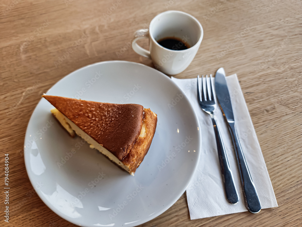 Fototapeta premium A slice of San Sebastian Cheesecake on a plate with a coffee in a cafe 