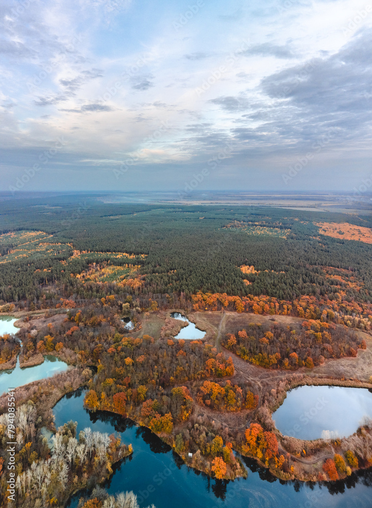 Aerial vivid autumn river scenery vertical panorama with forest on riverbanks and clouds in Ukraine