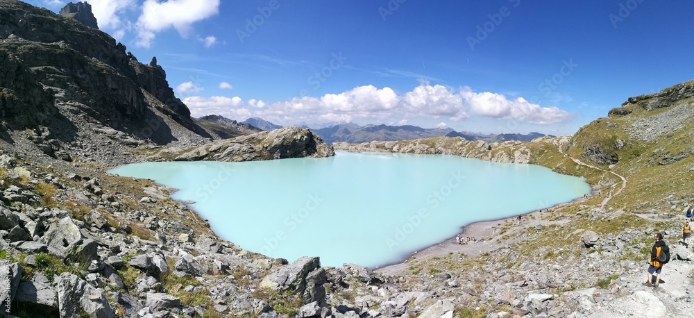 Wanderer looking at Schottensee lake with light blue water color, Alpine, Pizol hiking 5-lakes Switzerland