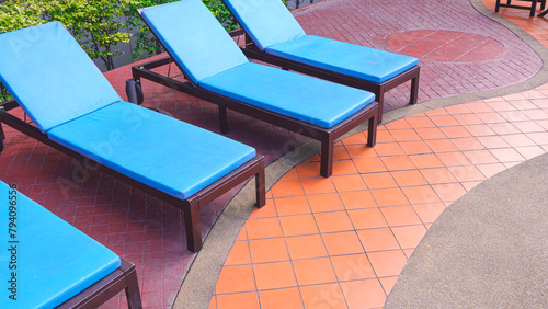 Row of blue sunbed lounger chairs on colorful curve lines pattern of stone tile floor decoration in poolside area at resort