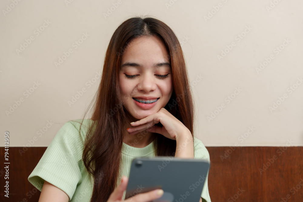Engrossed Asian woman reads from tablet, leaning on one hand, expression mixture of focus and contentment. Absorbed in digital reader, young supports chin with hand, serene atmosphere in study corner Engrossed Asian woman reads from tablet, leaning on one hand, expression mixture of focus and contentment. Absorbed in digital reader, young supports chin with hand, serene atmosphere in study corner