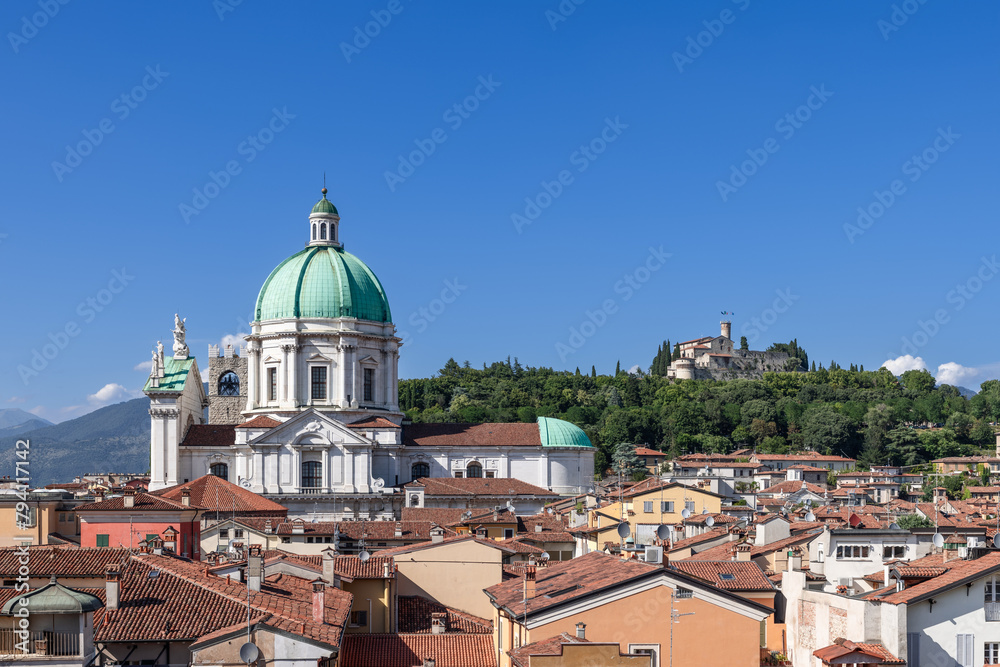 The architectural heritage of Brescia unfolds with the Cathedral of Santa Maria Assunta dome rising above rooftops, backed by the medieval castle atop a lush hill
