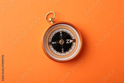 One compass on orange background, top view photo