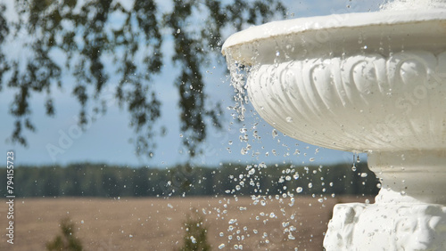 Decorative white fountain against a background of nature.