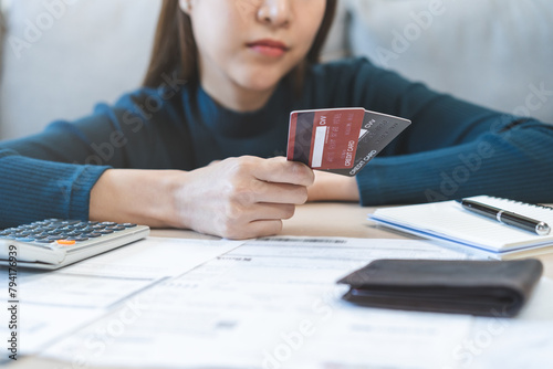 Business financial concept, stressed asian young business woman hand holding credit card for calculate accounting expense of bill, tax for payment on due deadline, trying to find money to pay debt.