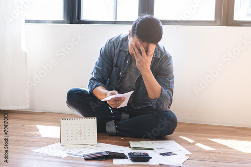 Financial concept, owe asian young man sitting suffer, stressed and confused by calculate expense from invoice credit card bill, no money to pay mortgage or loan. Debt, bankrupt or bankrupt people. photo