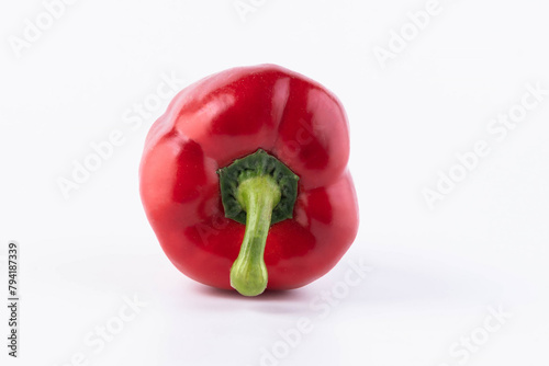 A red pepper lies with the green stalk down on a white background.