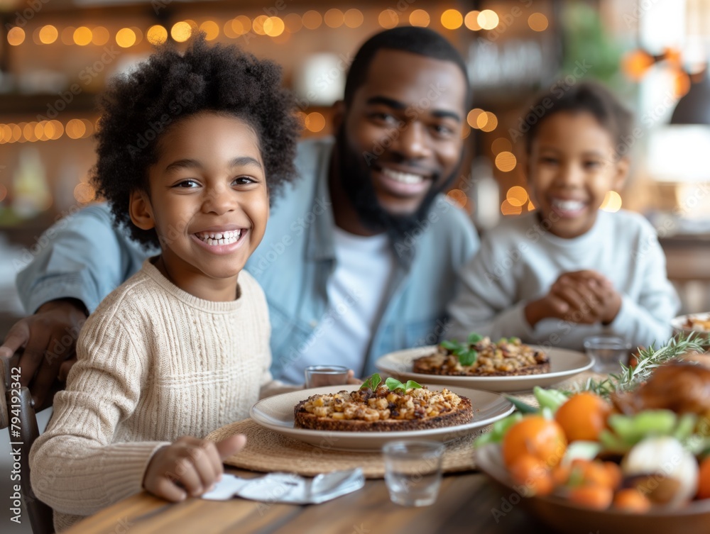 A family of three, a man and two children, are sitting at a table with plates of food in front of them. The man is smiling and the children are also smiling, creating a warm and happy atmosphere