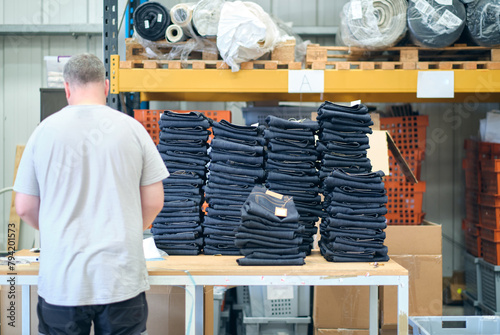 A pile of raw denim jeans fresh off a production line in a denim factory. Industrial fabric and fashion manufacture. Stylish blue denim fabric for wholesale. photo