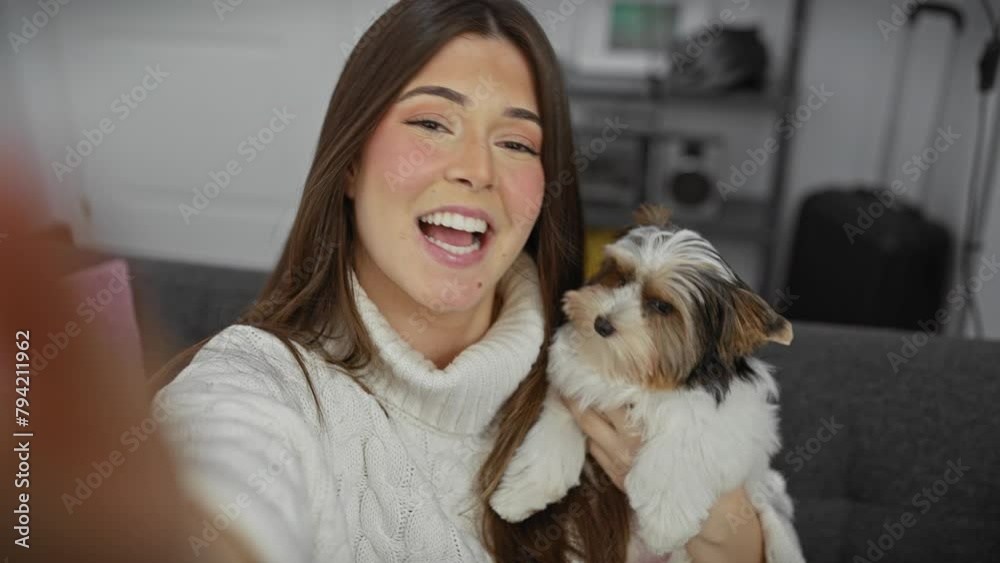 A smiling young woman holding a biewer yorkshire terrier in a cozy modern living room. A smiling young woman holding a biewer yorkshire terrier in a cozy modern living room.