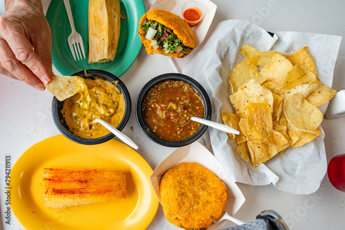 View from above of authentic Mexican meal from above featuring chips, tamales, guorditas and salsa.