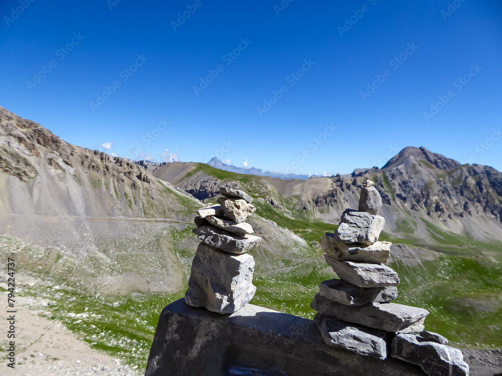 Close up view of pile of stones with scenic view of rifugio della Gardetta on Italy French border in Maira valley, Cottian Alps, Piedmont, Italy, Europe. Hiking on sunny summer day in nature