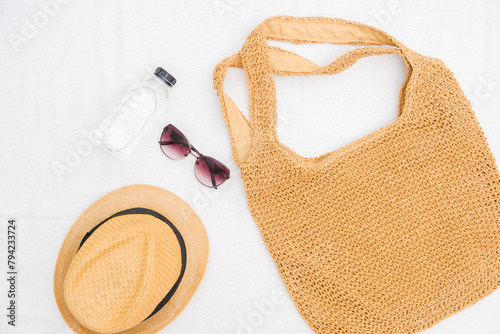 Straw bag for beach, bottle of water, straw hat and sunglasses on white background. Summer and beach accessories.