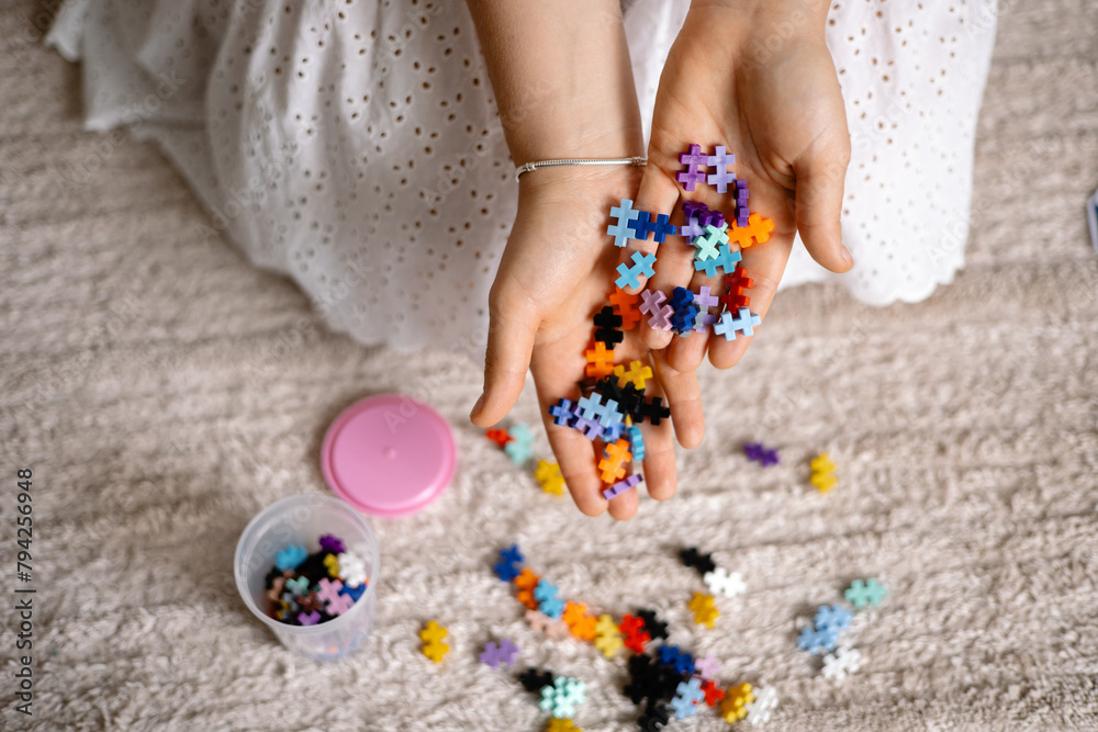 a multi-colored small puzzle set in a womans hands a multi-colored small puzzle set in a womans hands