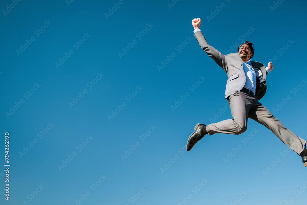 A man in a suit jumps energetically in the air, showcasing energy and excitement.