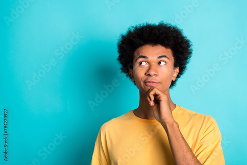Portrait of intelligent man with afro hairstyle wear oversize t-shirt thoughtfylly look empty space isolated on teal color background © deagreez