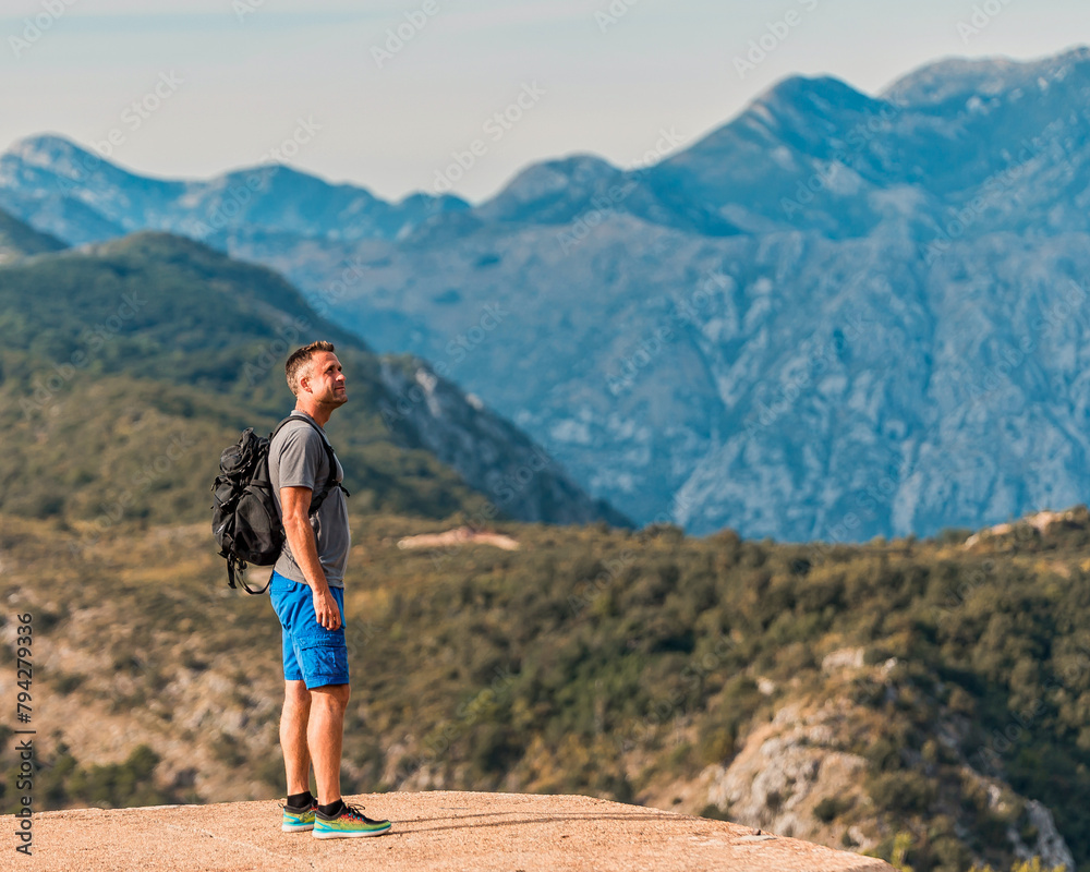 Fototapeta premium hiker with backpack standing on mountain peak overlooking a stunning mountain range