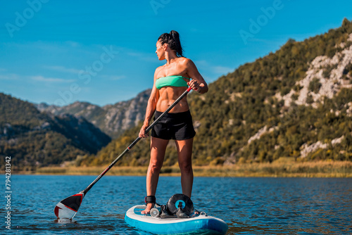 female paddler on inflatable sup board amidst stunning mountainous landscape and turquoise waters