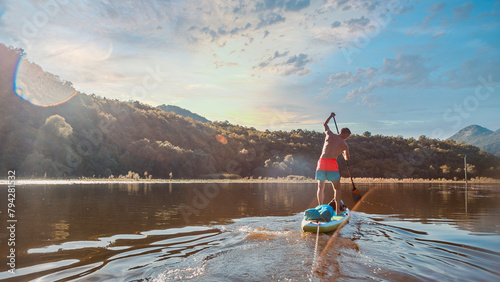 paddleboarding in serene river scenery with gentle sunrise rays