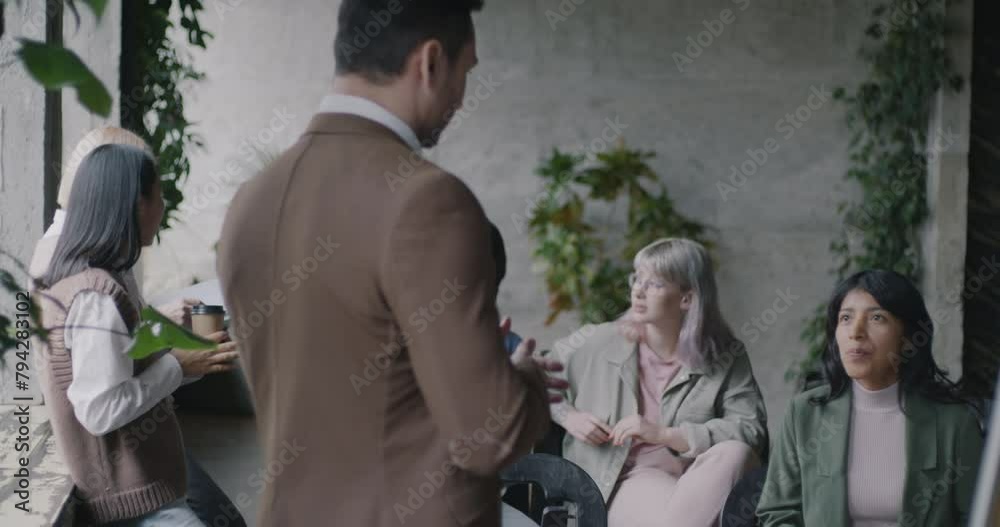 Diverse group of young businesspeople talking and laughing relaxing during work break in modern office. People and business concept. Diverse group of young businesspeople talking and laughing relaxing during work break in modern office. People and business concept.