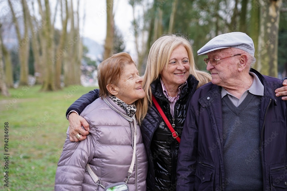 a family hugging in a park. The family consists of a daughter and her parents a family hugging in a park. The family consists of a daughter and her parents