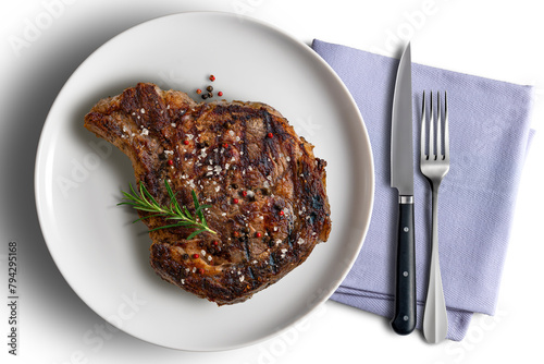 Whole rib eye beef on a flavored white round plate with cutlery and napkin
