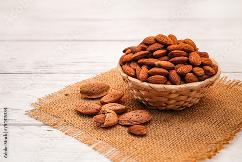 Almonds in Wicker Basket Bowl on White Wooden Table. Almond Concept with Copy Space