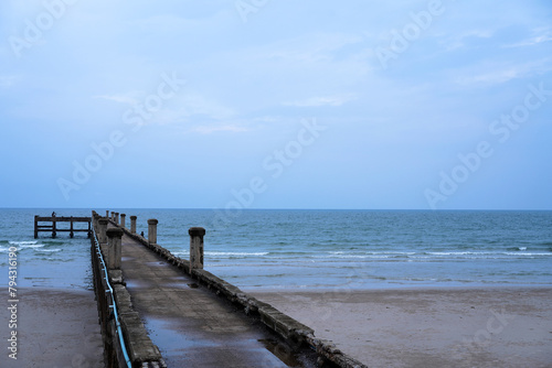 One fishing man on the old long concrete pier extending out into the ocean with cloudy in the sky background in Chumphon Province  Thailand.