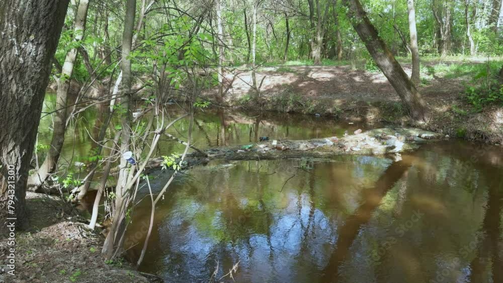 Garbage floating along quiet forest river collects near fallen tree. Water pollution. Garbage floating along quiet forest river collects near fallen tree. Water pollution.