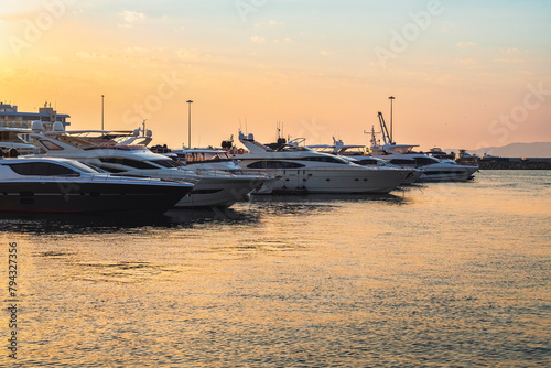 Yachts and boats on the dock at the seaport at sunset