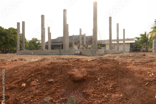 A construction site with a house in the background. The house is being built with cement blocks. The construction site is located in a rural area