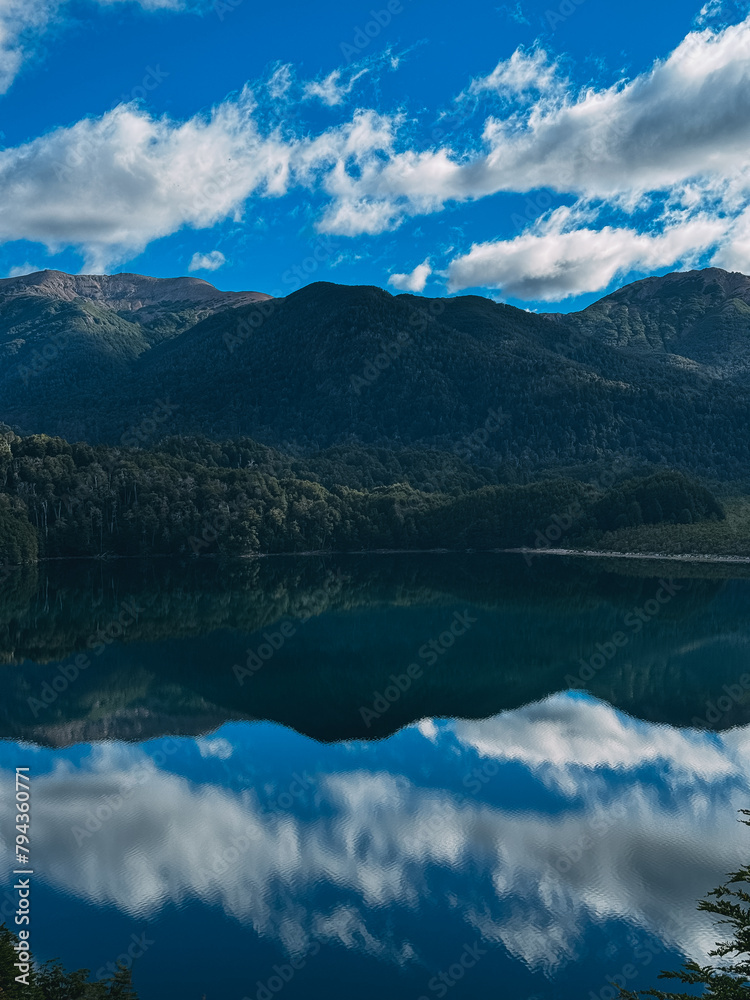 A beautiful mountain lake with a blue sky in the background. The lake is calm and peaceful, with the reflection of the mountains in the water. Concept of tranquility and serenity
