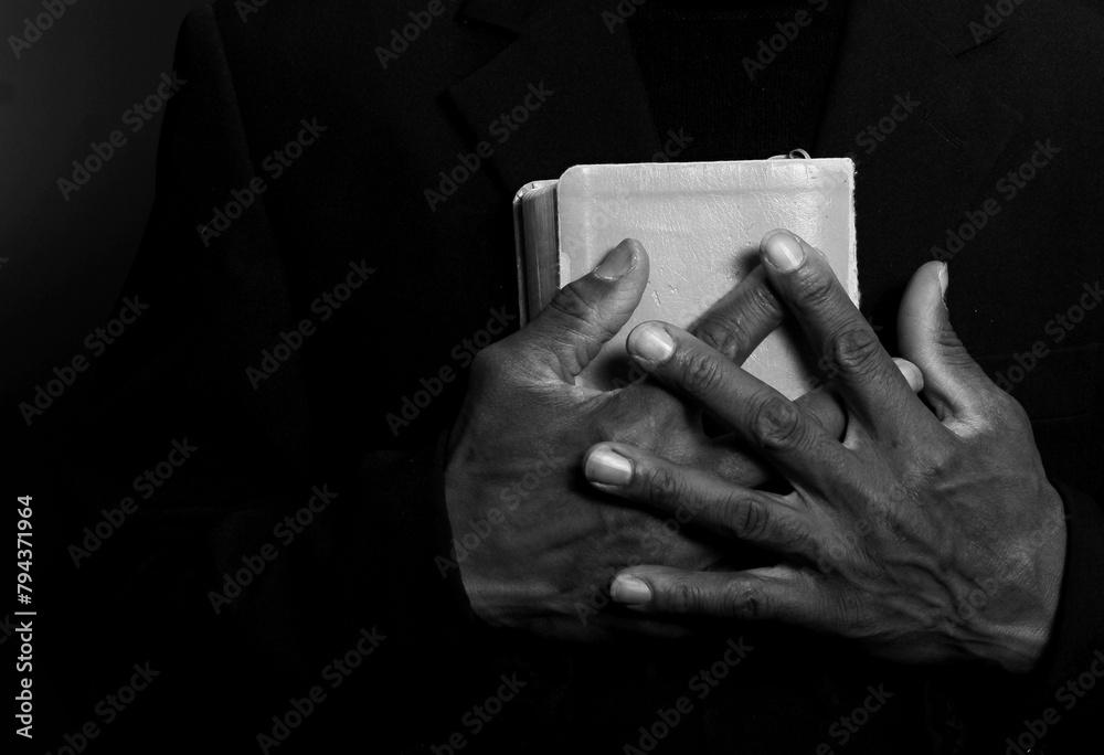 man praying to god with hands together on dark background stock photo	