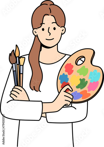 Woman artist holds brushes for painting and palette for mixing watercolor paints. Portrait of beautiful artist girl who is interested in creative hobby and wants to exhibit in art gallery