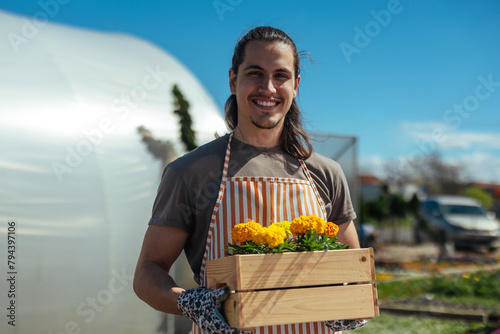Smiling man holding wooden box of flowers photo