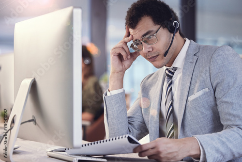 Headache, agent and telemarketing by computer for target, tension and deadline in office. Call centre, man and frustrated with script for client, CRM and technical support at desk in company photo