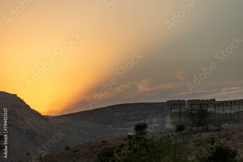 Warm sunset casting a glow over the remains of an ancient structure in a desert landscape, Ranikot, Sindh, Pakistan photo