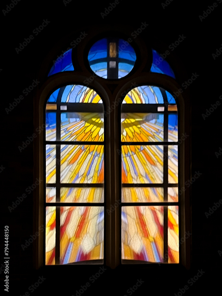 Stained glass window in the church of St. Józefa in Kaeta Jedrysek, at night with the interior of the church illuminated.